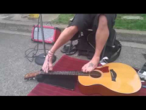 Уличный музыкант без рук играет на гитаре.
